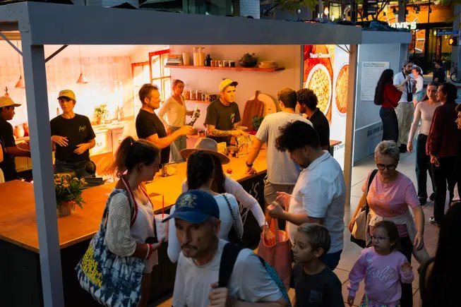 Santa Monica’daki Amy’s Kitchen kampanya enstalasyonunda tezgâh başında toplanan yetişkin ve çocuk ziyaretçiler