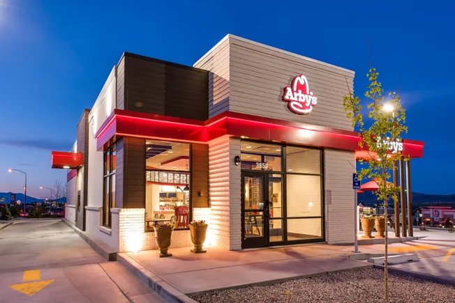 Akşam saatinde ışıklandırılmış bir Arby’s restoranının dış cephesi