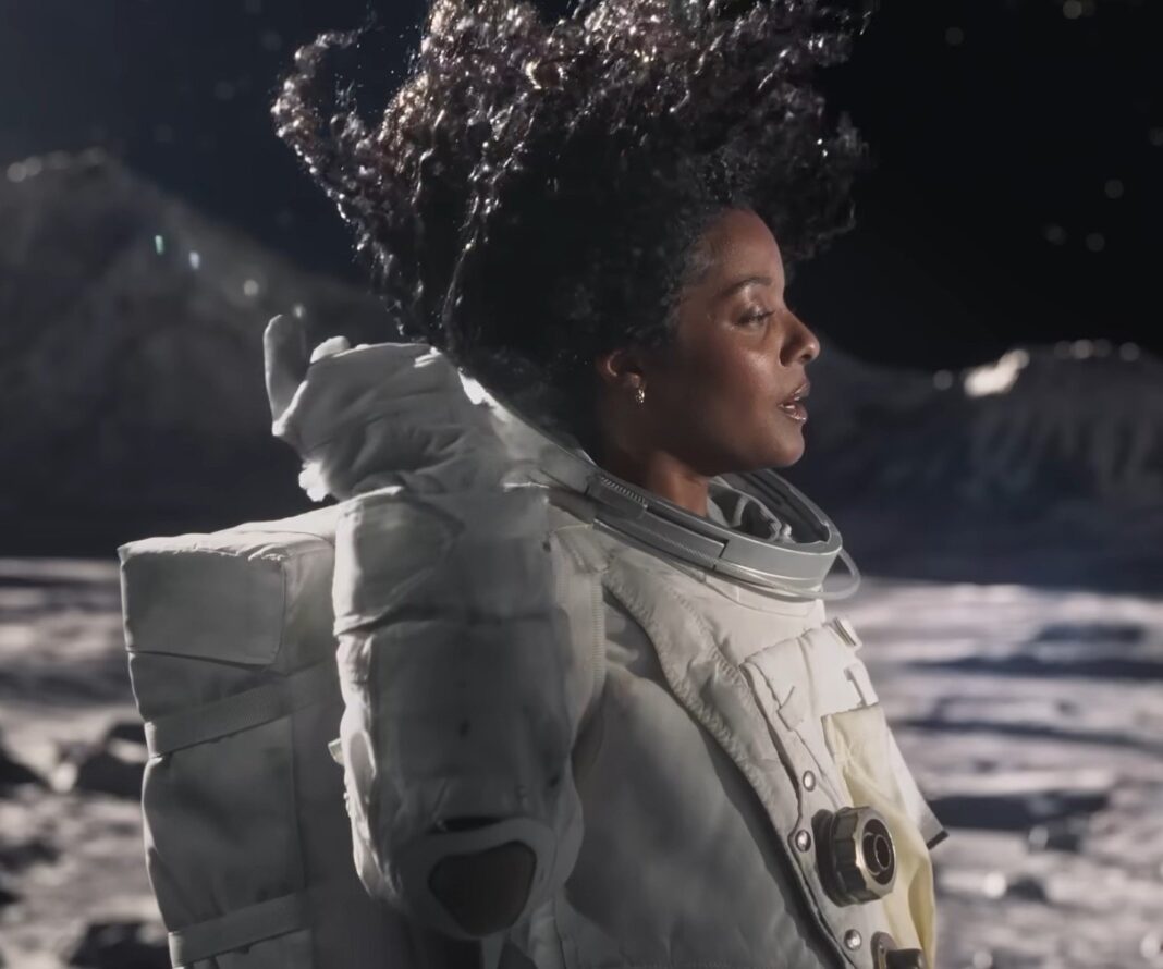 e.l.f. Cosmetics reklamından bir kare: Ay yüzeyinde kaskını takmamış, saçları havada dalgalanan bir astronot