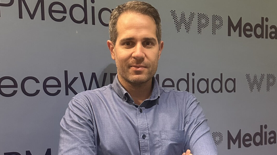 WPP Media logolu bir arka planın önünde mavi gömlekli Haluk Akalp