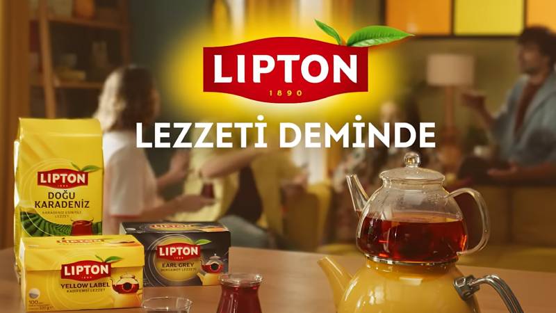 Lipton’un “Lezzeti Deminde” görselinde çay paketleri, demlikte çay ve arka planda sohbet eden aile