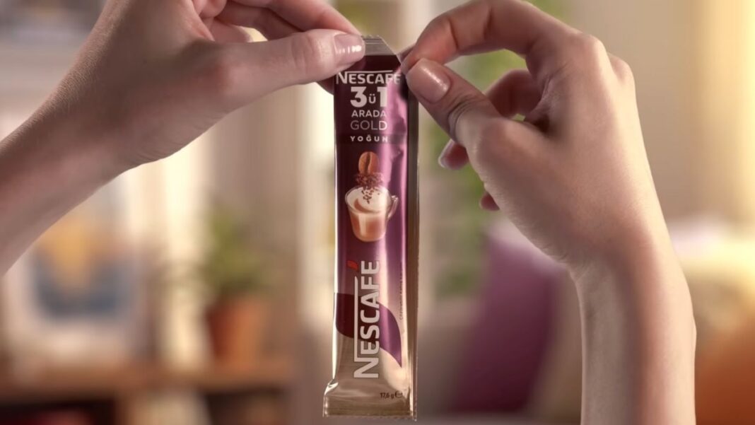 İki elin arasında açılmak üzere tutulan NESCAFÉ 3ü1 Arada Gold paketi